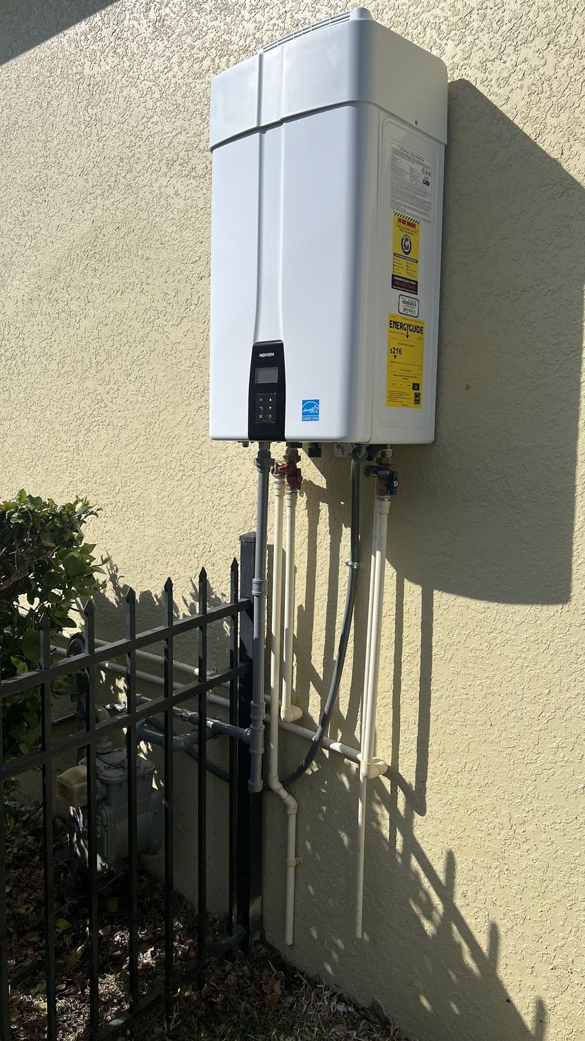 Choice Plumbing Orlando Navien tankless water heater installed outdoors on a Central Florida home — wall-mounted on-demand unit with new gas and water connections
