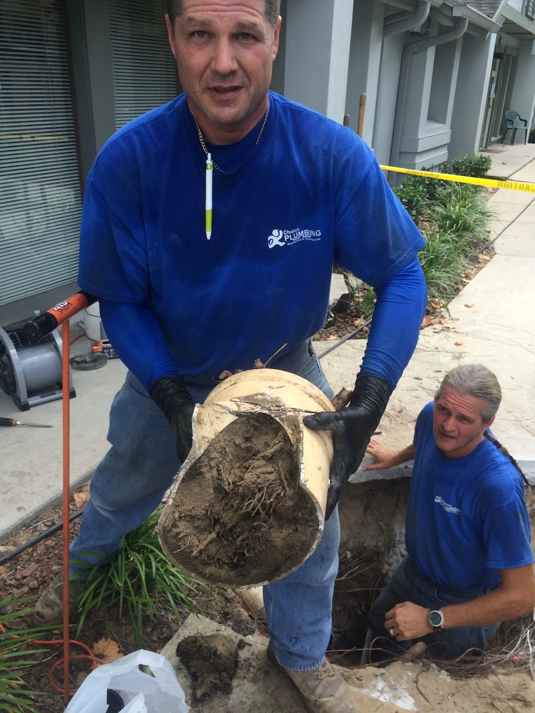 Choice Plumbing technician holding a sewer pipe packed solid with tree roots in Orlando