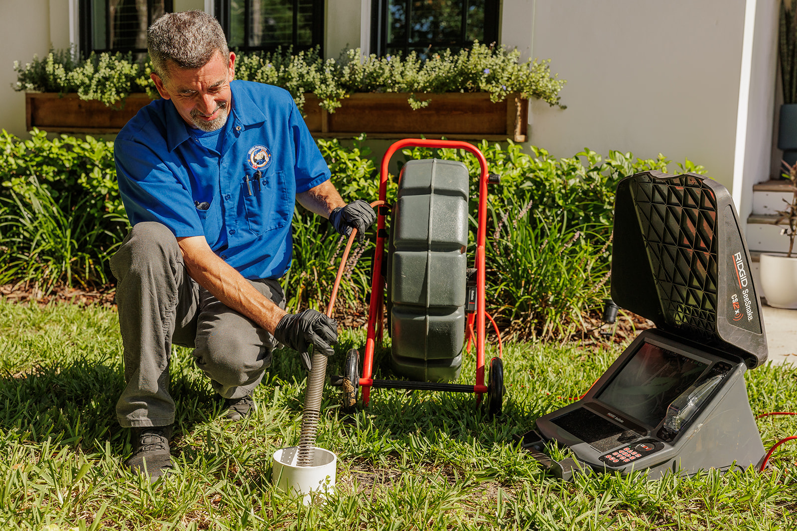 Choice Plumbing Orlando licensed technician running a RIDGID SeeSnake sewer camera through the cleanout of an older Winter Park home — cast iron sewer inspection in Winter Park Pines / Lakemont / Olde Winter Park