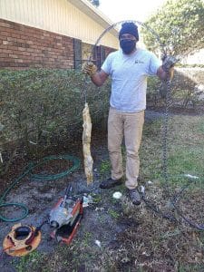 Plumber removing blockage from a clogged toilet drain pipe