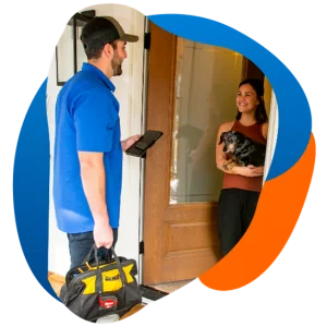 Technician arriving at a customer's home, greeted by a smiling woman holding a dog.